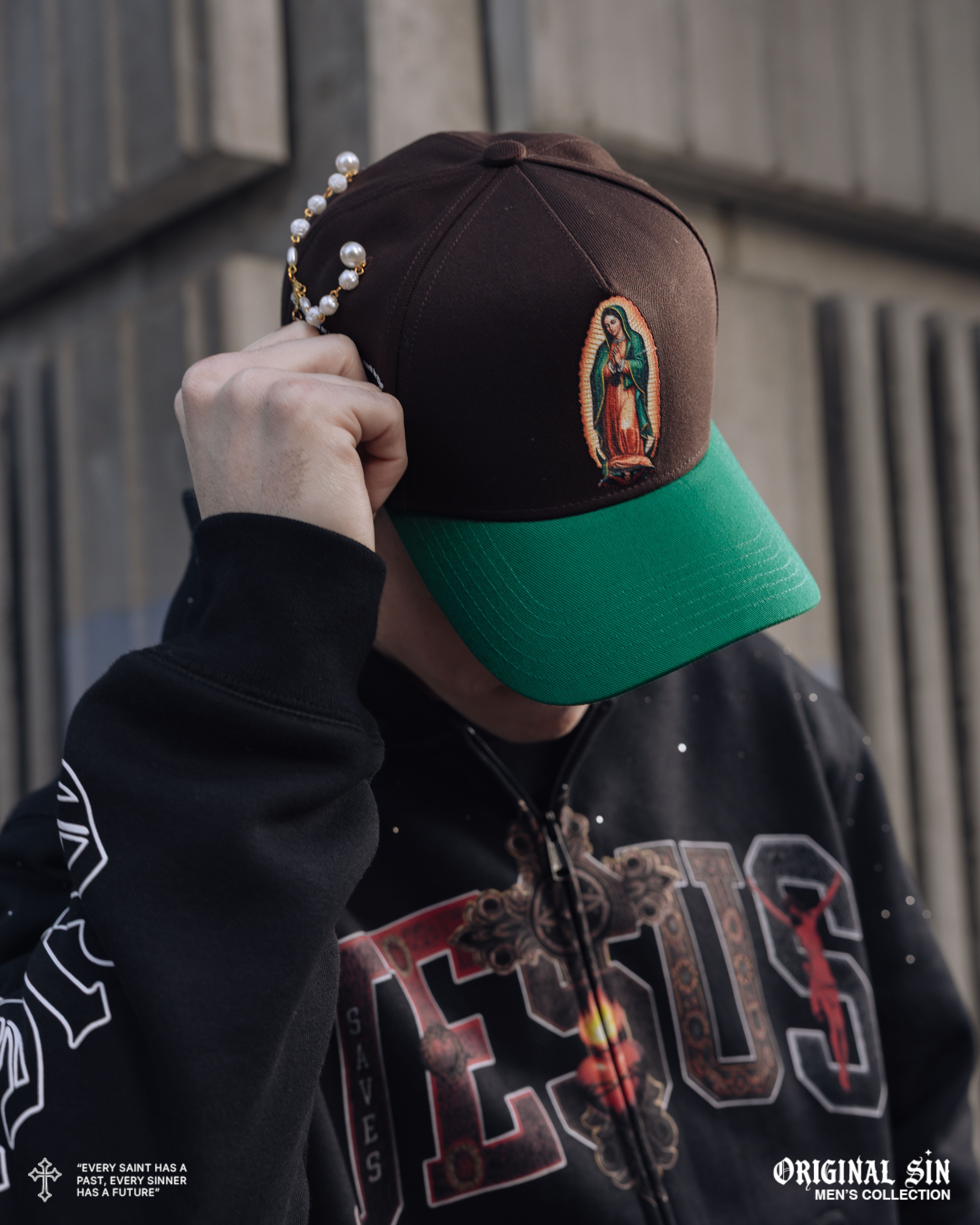 Person wearing a brown cap with a green brim and a black hoodie.