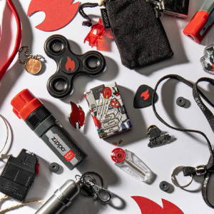 Lifestyle image of Zippo I Spy 540 Color Windproof Lighter, laying within a handful of Zippo themed items.