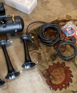 Black train horn kit and air tank components laid out on floor