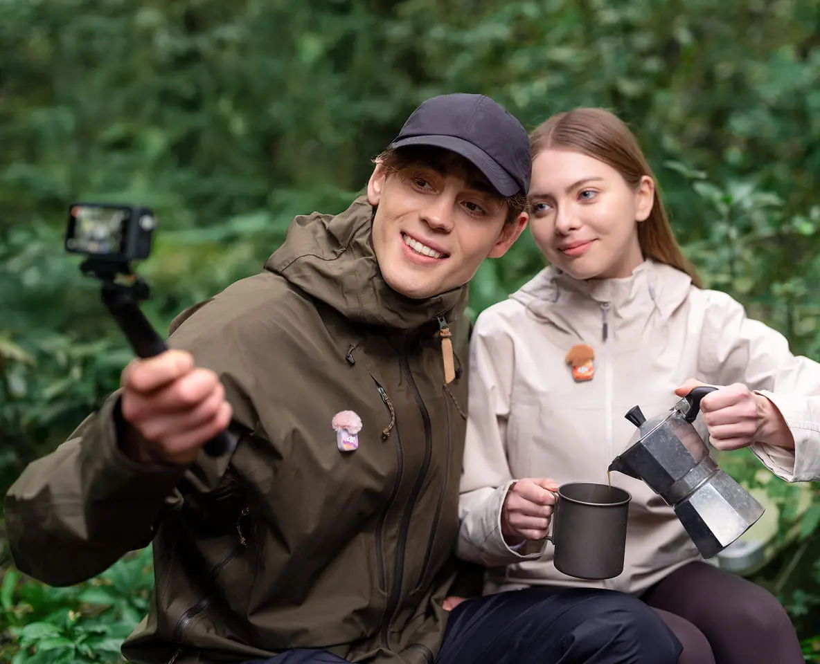Two people enjoying nature, taking a selfie with a DJI Osmo Action camera, and holding a coffee mug.
