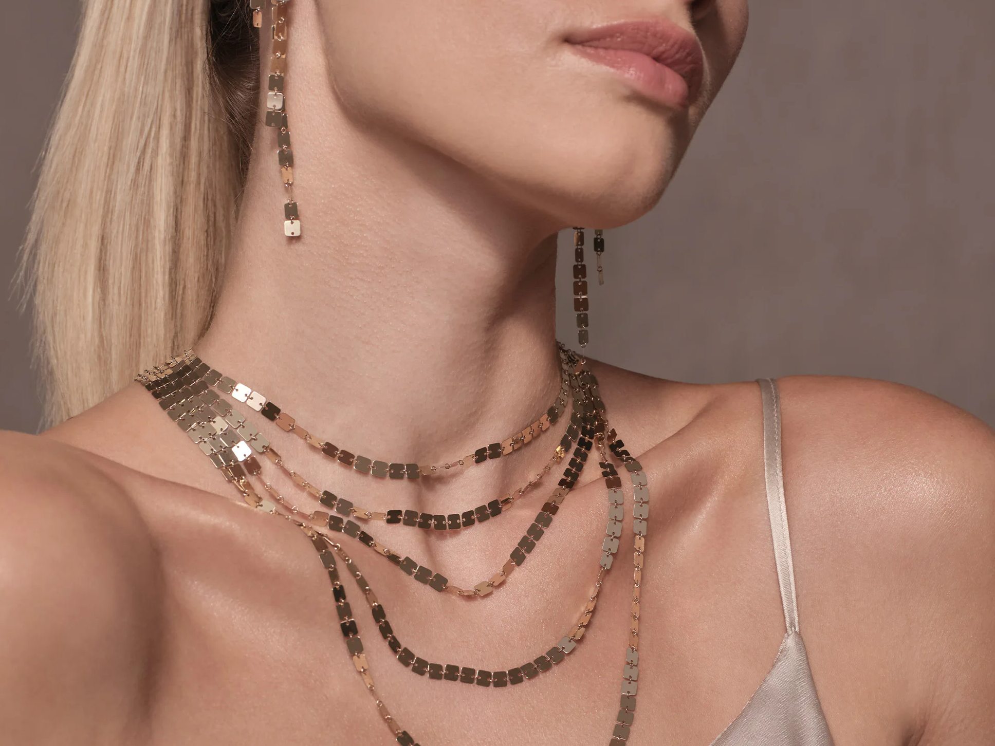 Close-up of a woman wearing layered necklaces and earrings.