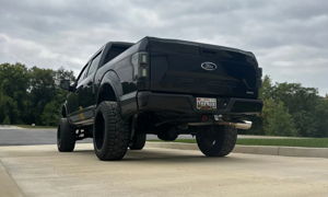 Rear view of Tanner's lifted black Ford F-150 Sport 4x4 with off-road tires parked on concrete