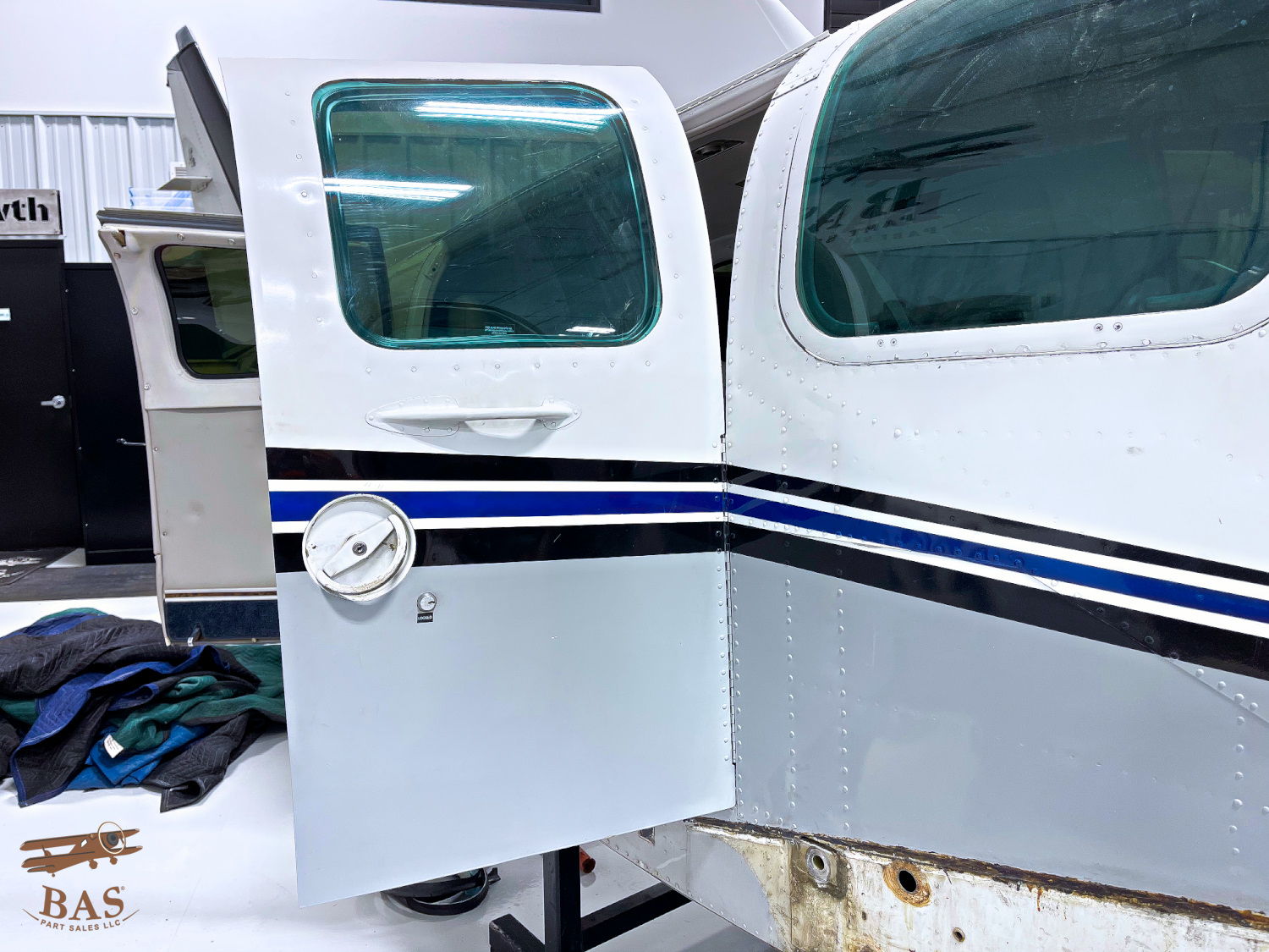 Aircraft door with windows and blue stripe, partially open.