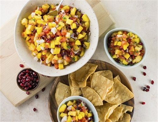 Colorful fruit salad with tortilla chips and pomegranate seeds.