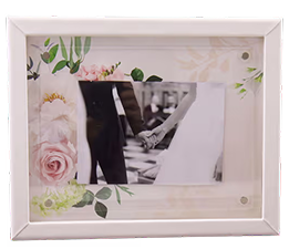 Black and white photo of two hands holding, framed with floral decorations.