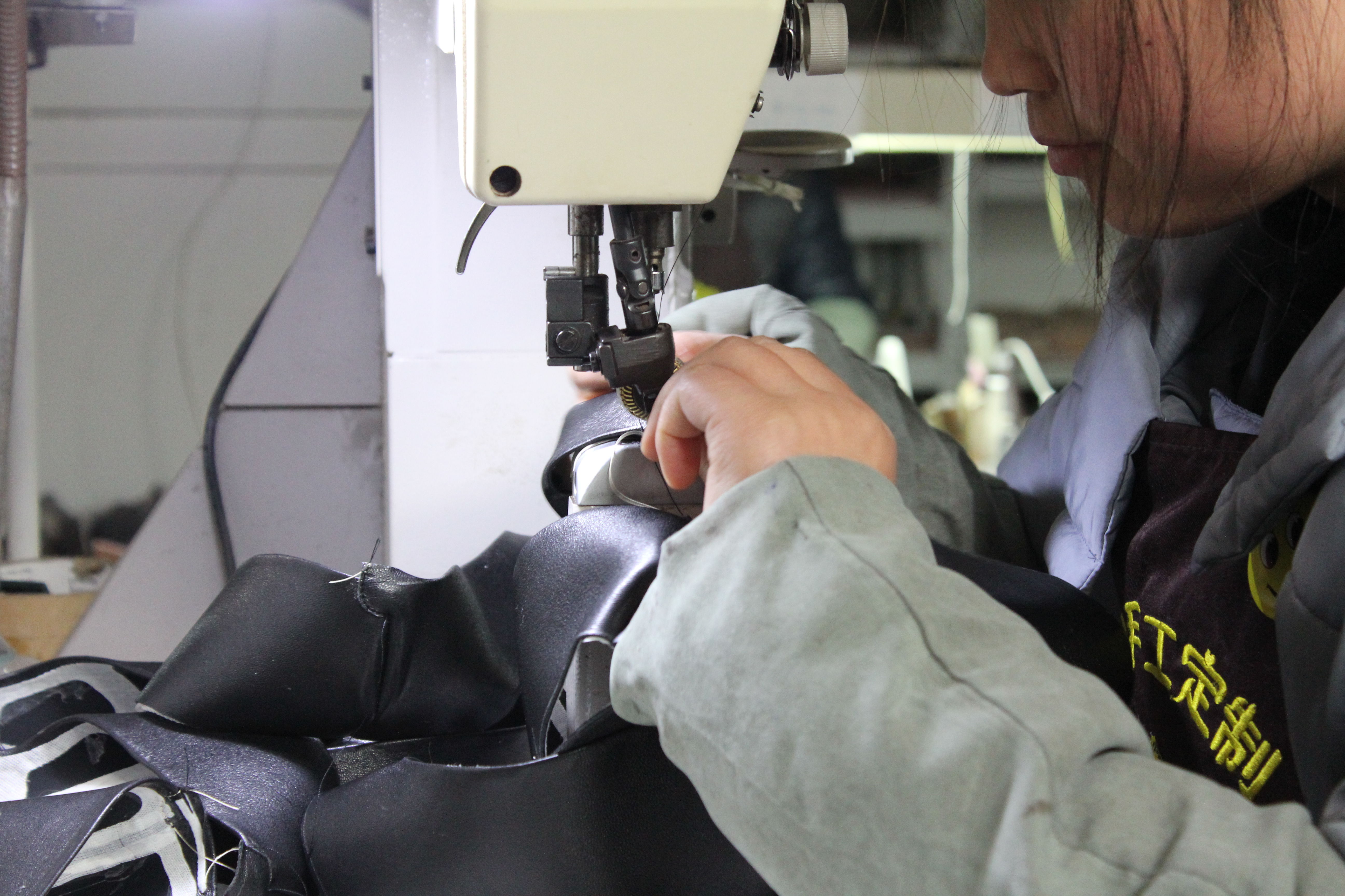Person sewing fabric with a sewing machine in a workshop setting.