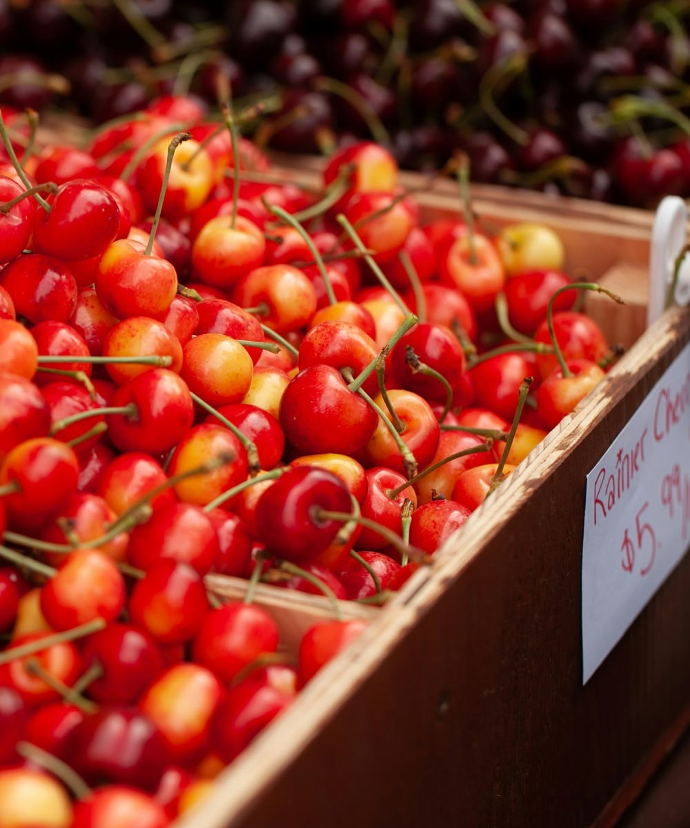 A box of bright red cherries at a market stall.