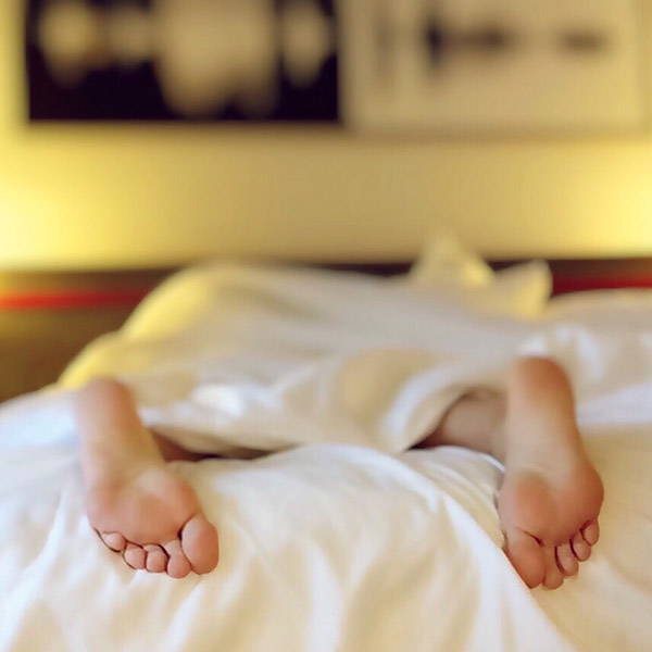 two bare feet peeking out from under the blanket