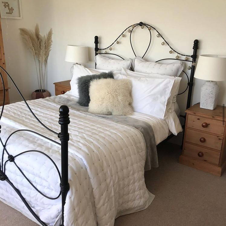Bedroom with switched off fairy lights displayed around the edge of the bedframe