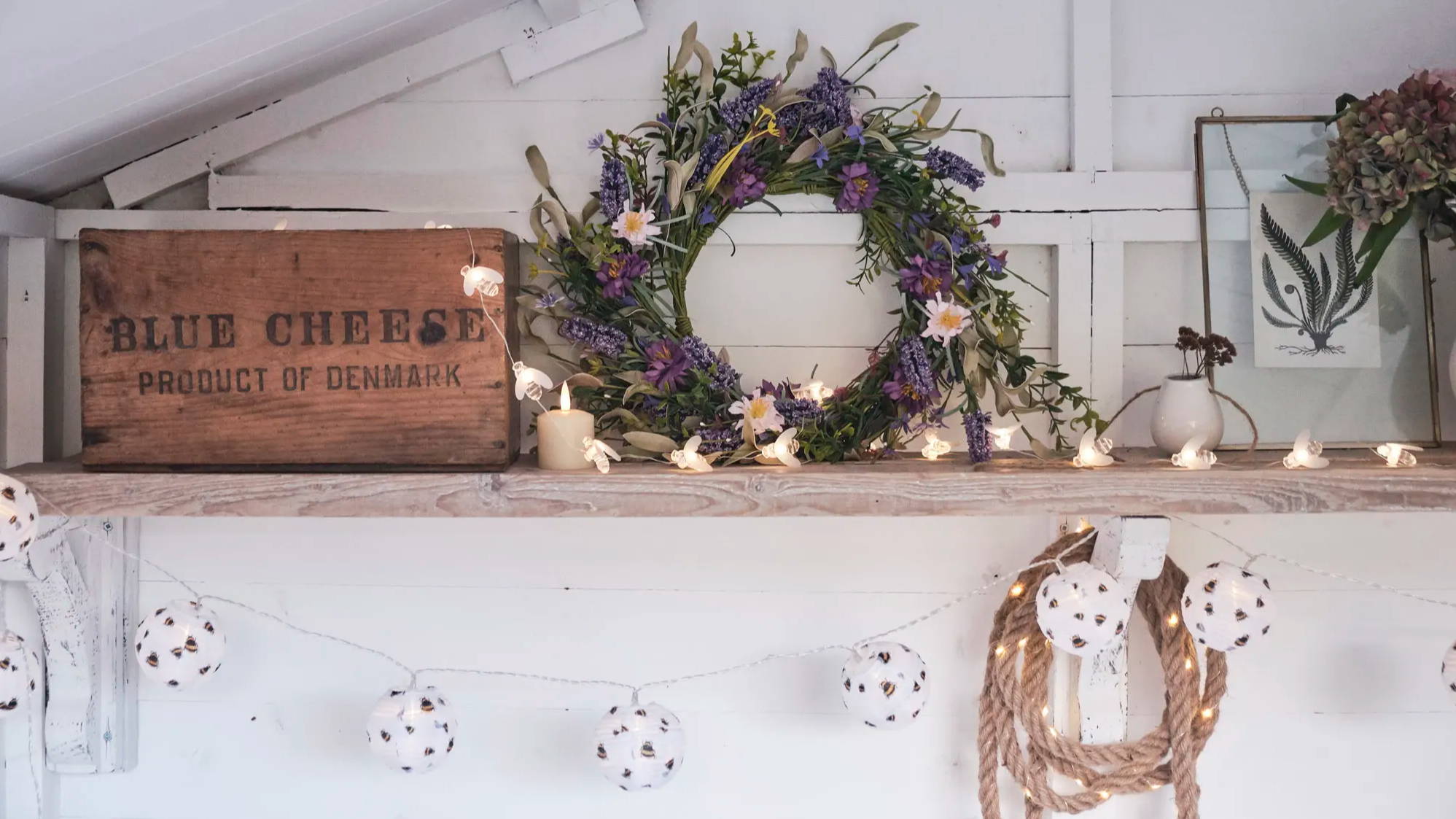 Lavender wreath, bee fairy lights and bee lanterns displayed on shelf 