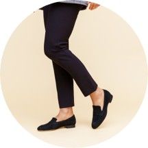 Person wearing black shoes and dark pants against a light background.