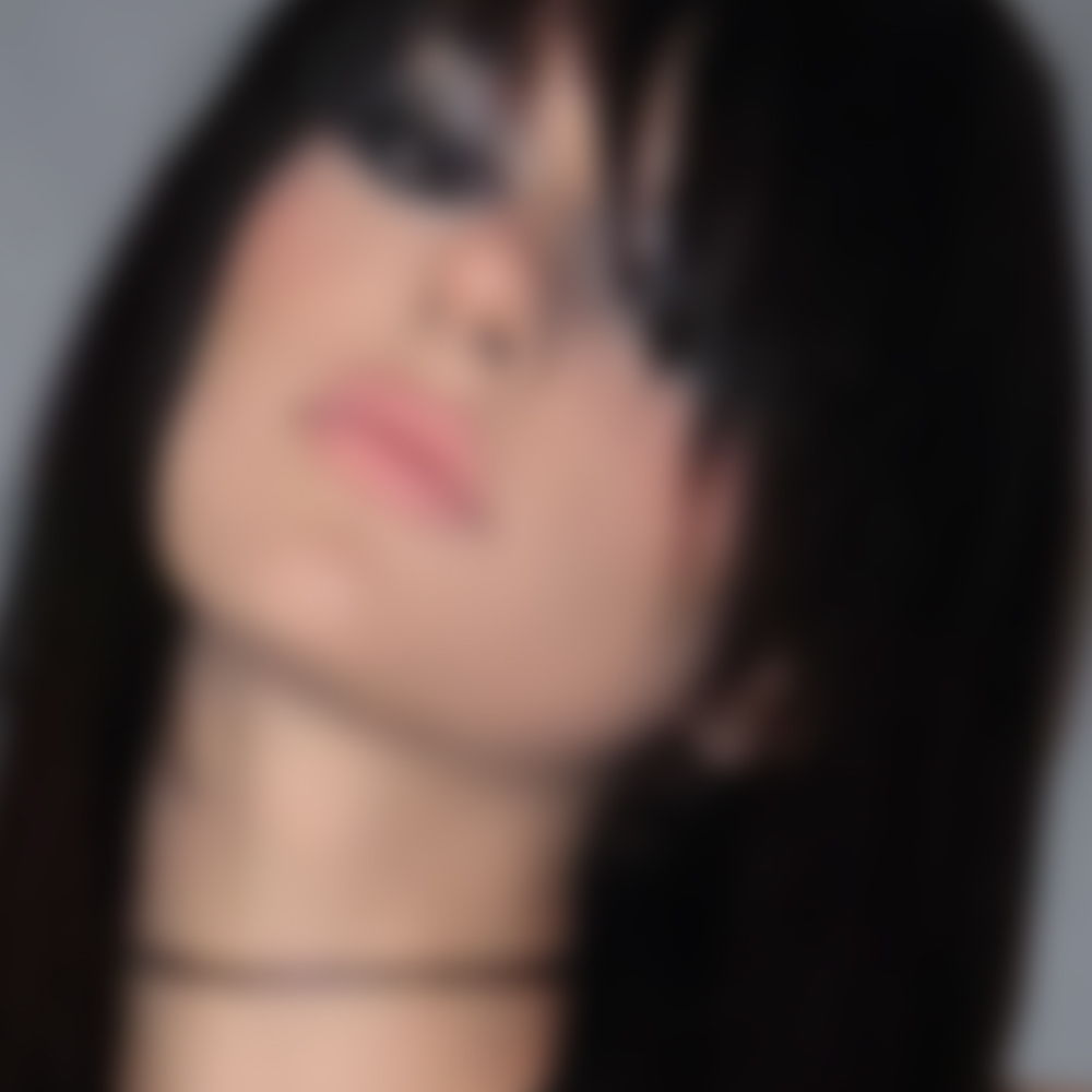 Blurred image of a woman with long dark hair and smoky eye makeup.