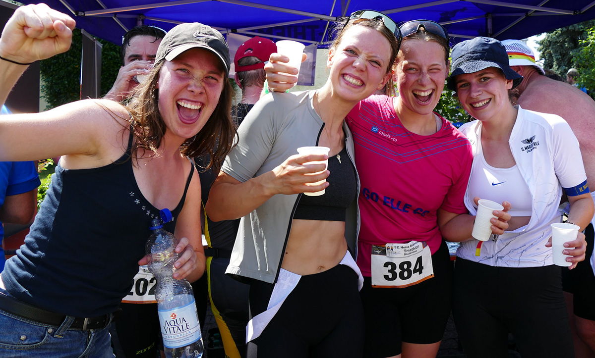 Jubelnde Frauen werden bei einem Triathlon im Ziel fotografiert.