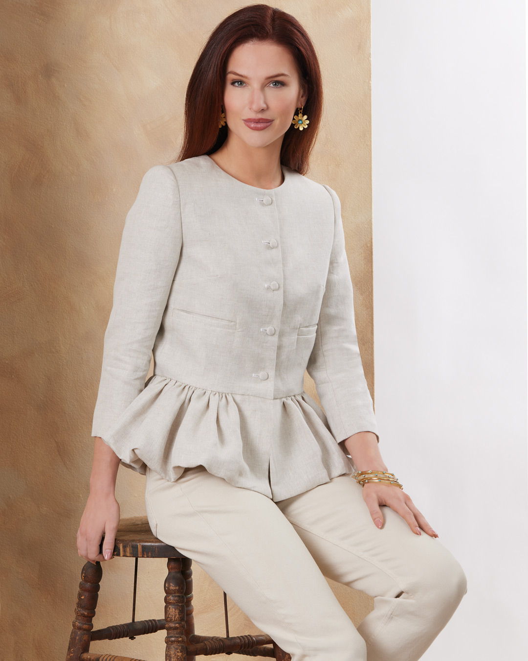 Woman in a stylish light jacket seated on a chair.