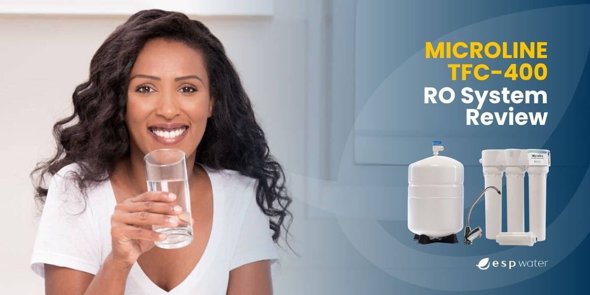 Woman smiling while holding a glass of water next to a water filtration system.