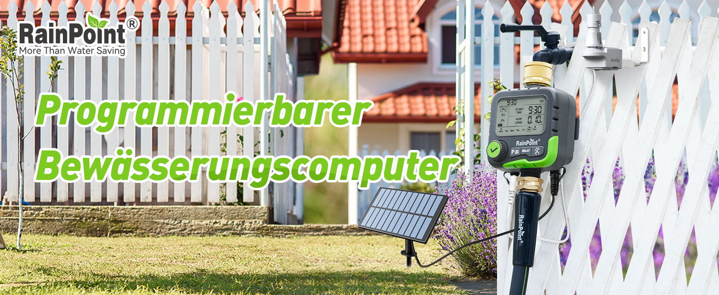 Programmable irrigation computer next to a white fence and red-roofed houses.