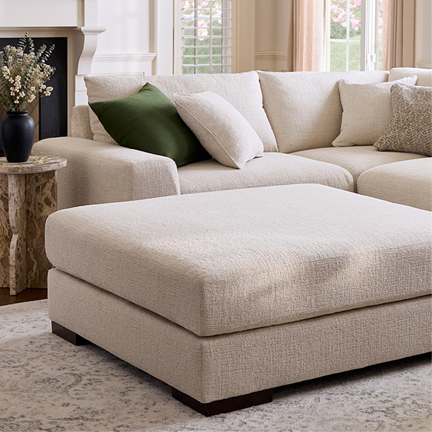 Light-colored sectional sofa with chaise and neutral-toned accent pillows in a bright living room.