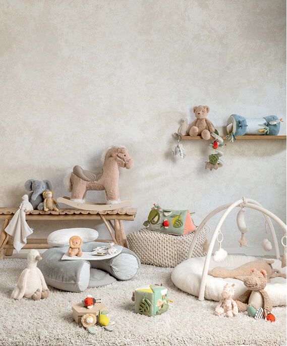 Nursery scene with toys, a baby on a soft rug, and pastel decor.