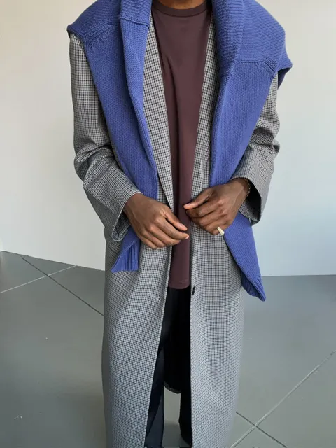 Person wearing a stylish gray and blue coat with a maroon shirt underneath.