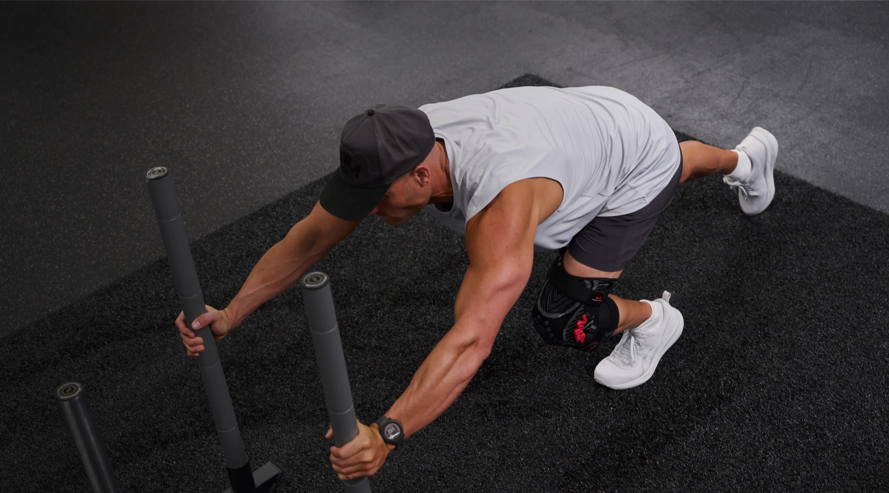 Person exercising with sled push equipment on a gym floor.