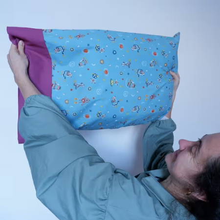 women holding a homemade pillowcase in the air made out of blue and fuchsia fabrics