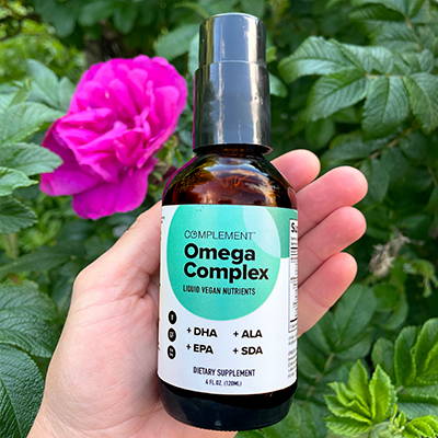 Hand holding Complement Omega Complex bottle.