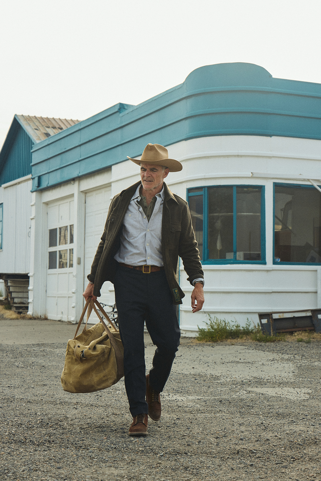 Michael Kelly walking through Livingston, Montana wearing the Meade Wool Glen Plaid Overshirt in Olive Drab and the Rivay X Alden Bedford Boot in Rough out Suede