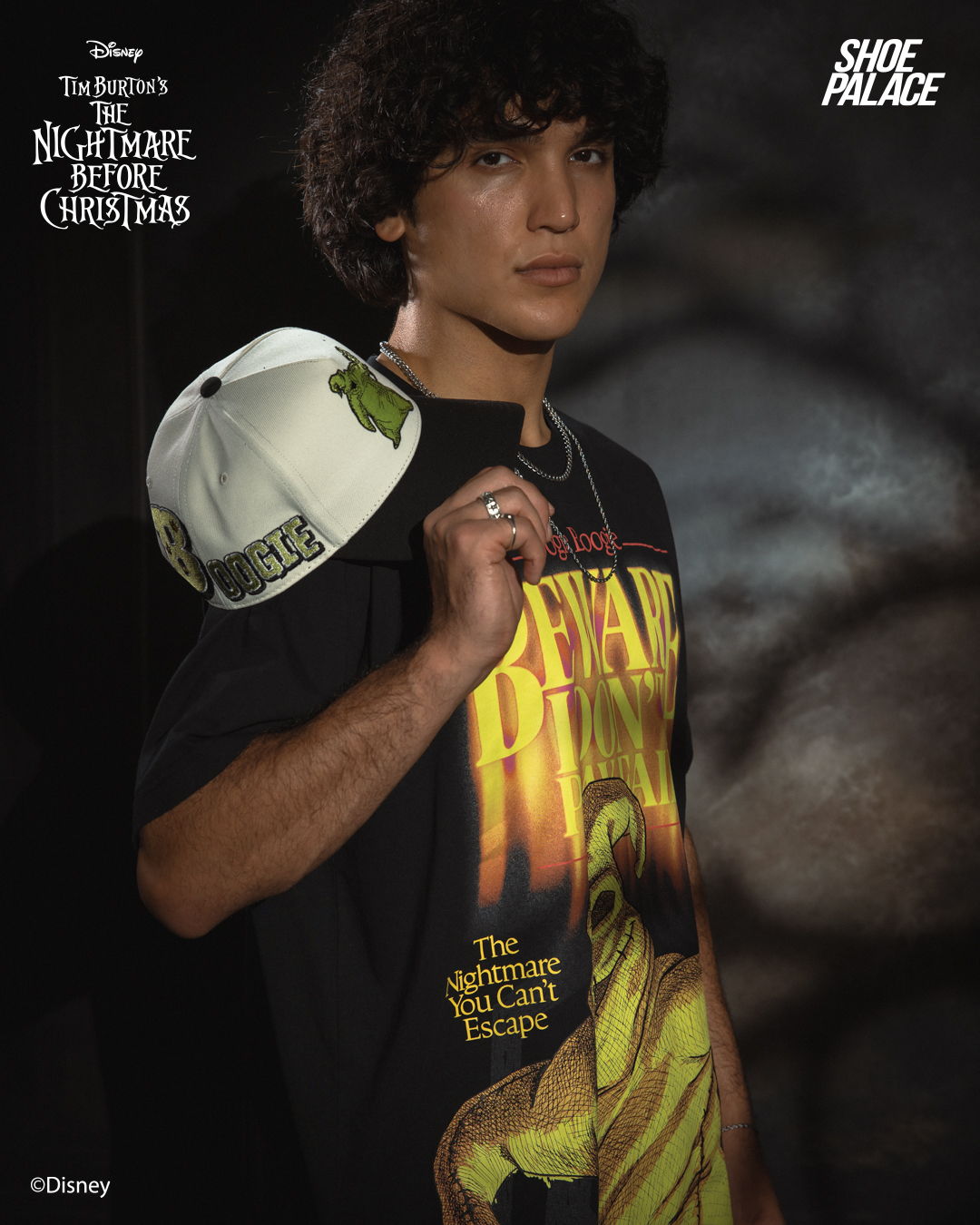 Young man wearing a Nightmare Before Christmas shirt and holding a hat.