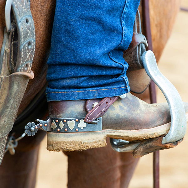A close-up of a cowboy boot in a stirrup.