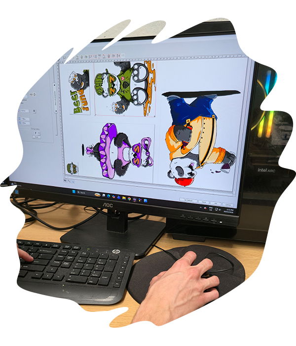Person using a computer mouse at a desktop, with a monitor displaying multiple colourful cartoon character DTF artwork files ready for printing