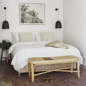 A cozy bedroom with a large bed, wooden bench, and decorative artwork.