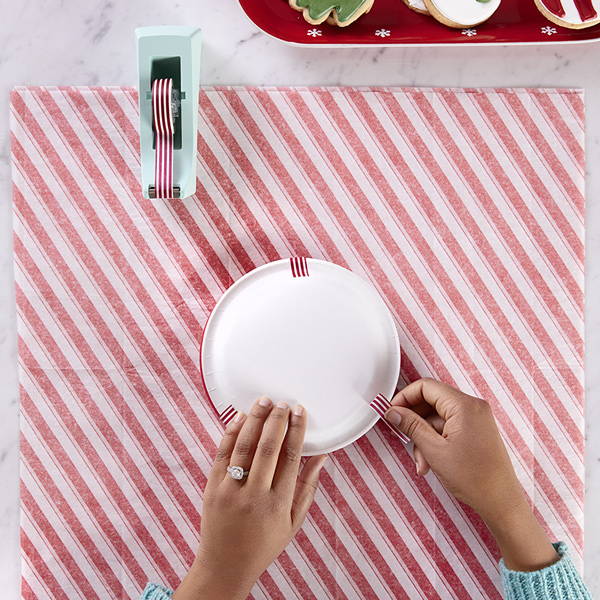 hands attaching washi tape on paper plate