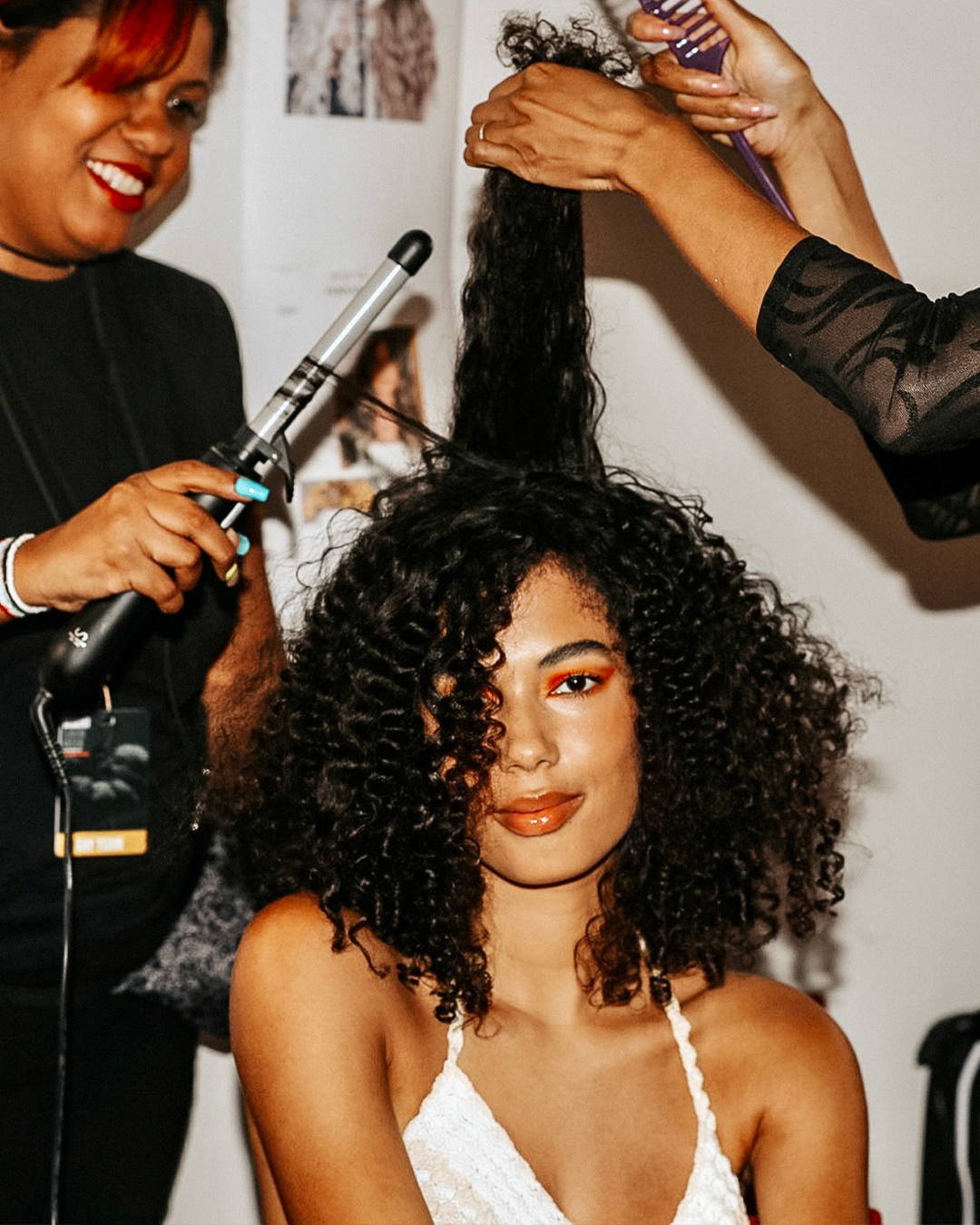 Image of Model with tight curls getting her hair touched up backstage at Miami Swim week with the S.75