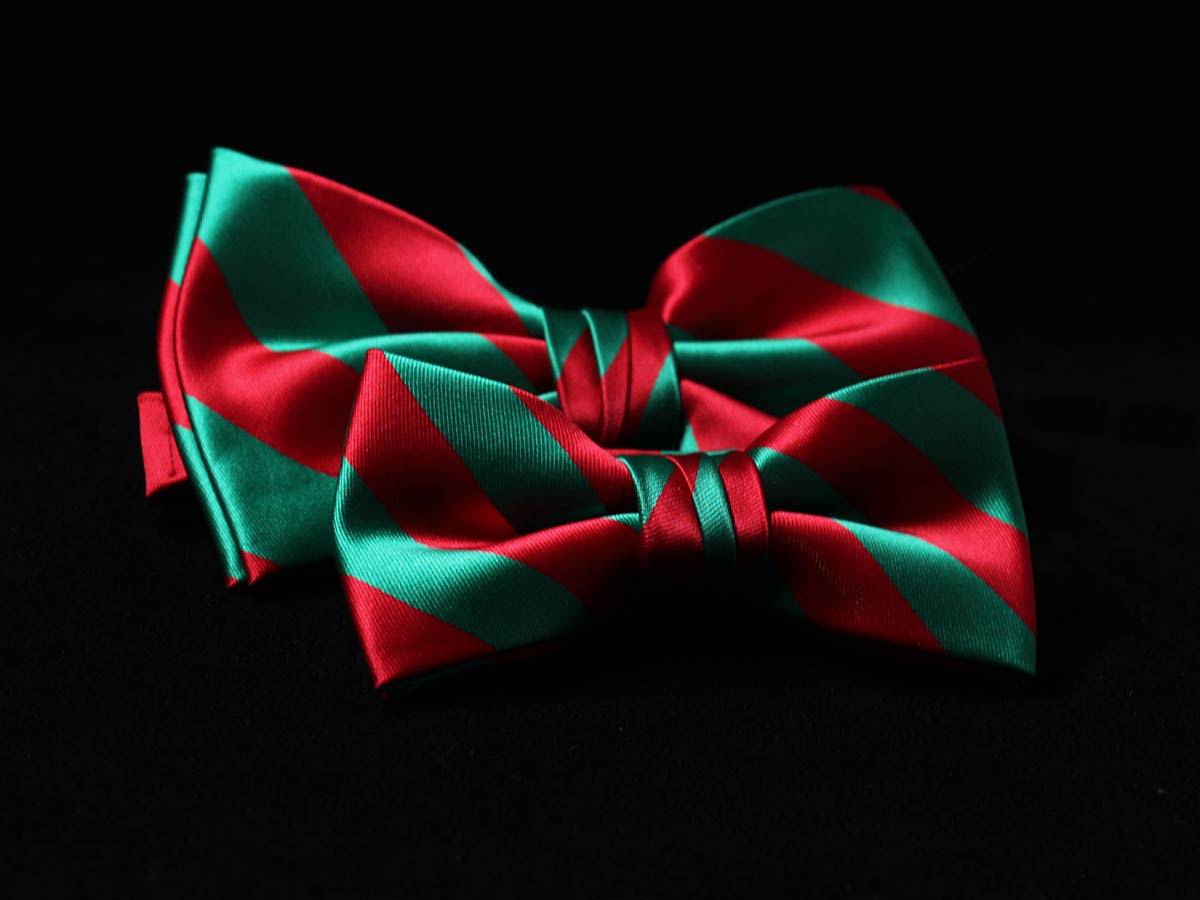 Matching red and green striped bow ties for men and boys on a black background