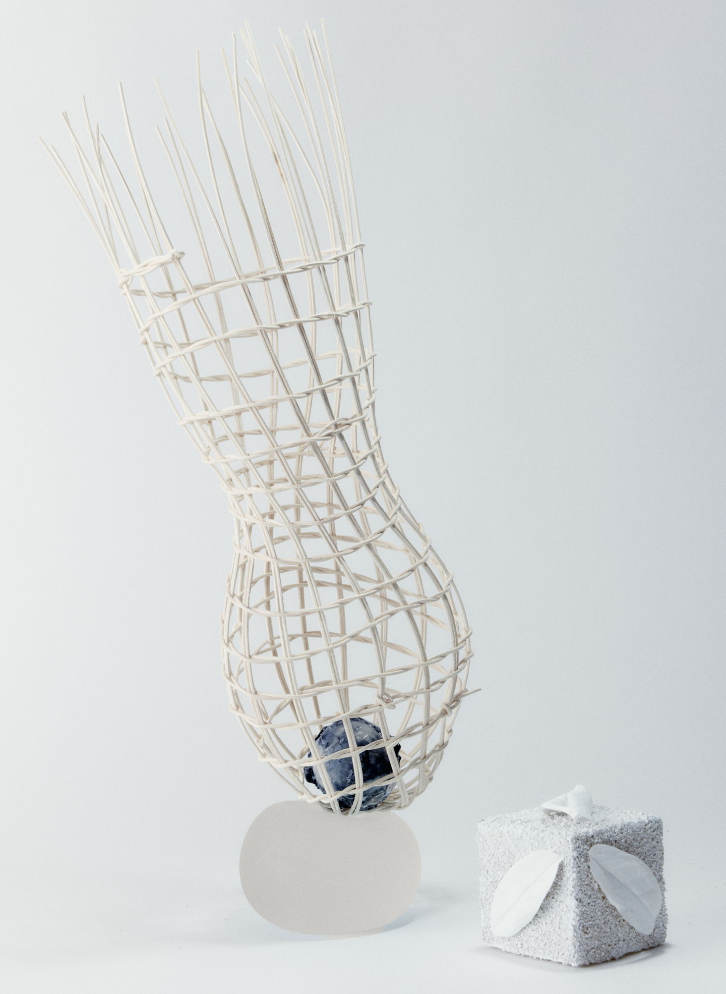 A sculptural piece with a woven structure and a gift box.