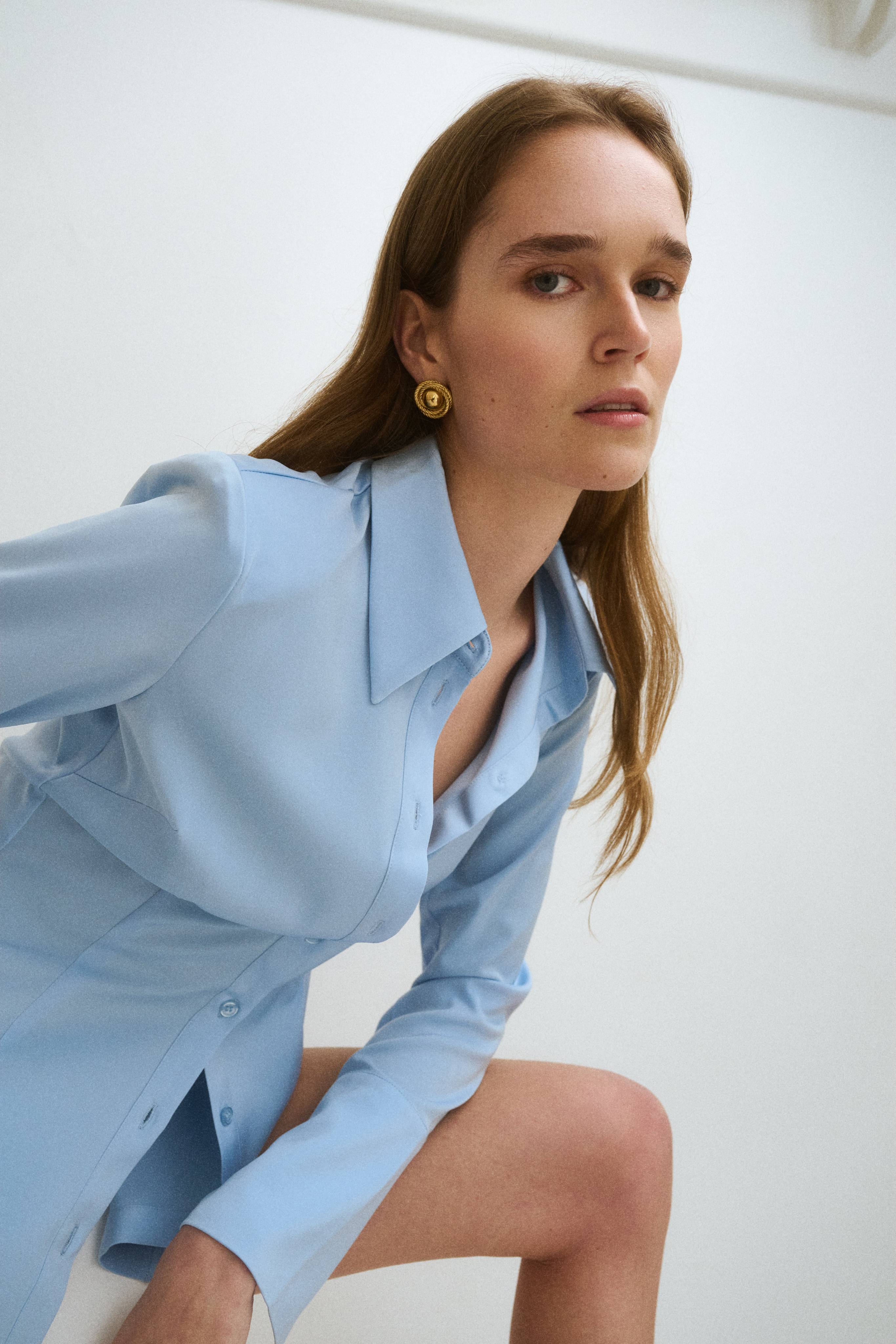 A woman in a blue shirt poses against a neutral background.