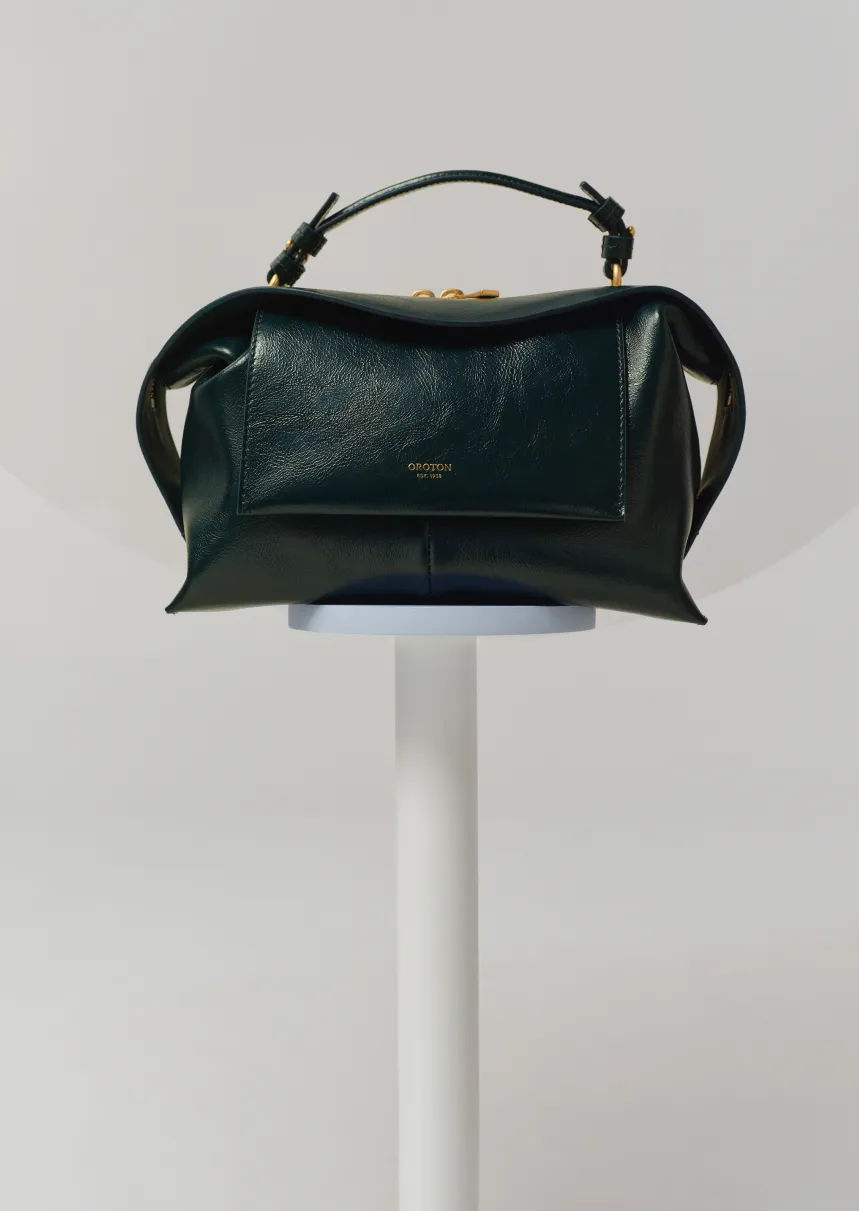 A stylish black leather handbag displayed on a pedestal.