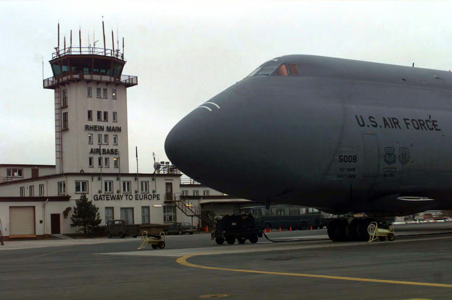 A large aircraft near an airport control tower on an overcast day.