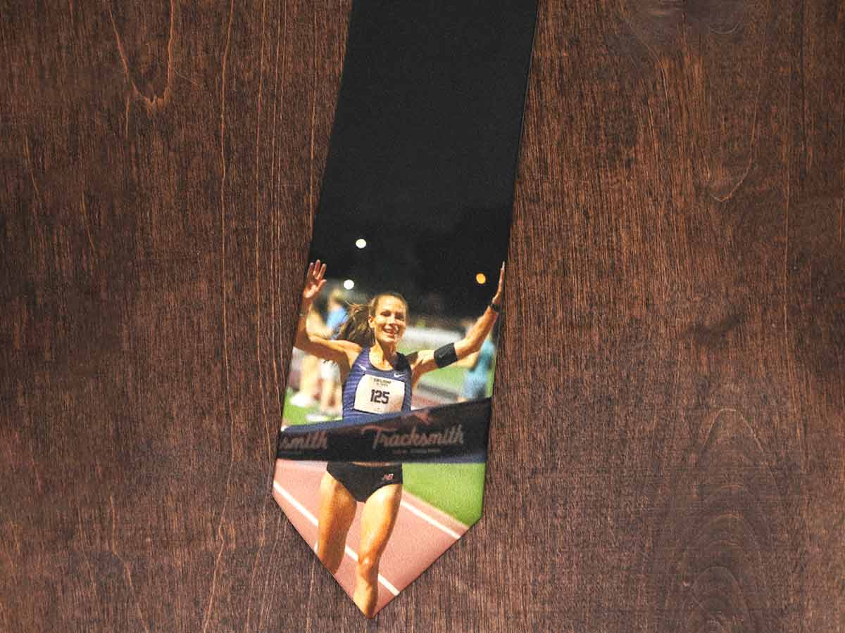 A black necktie with a photo of a runner crossing a finish line