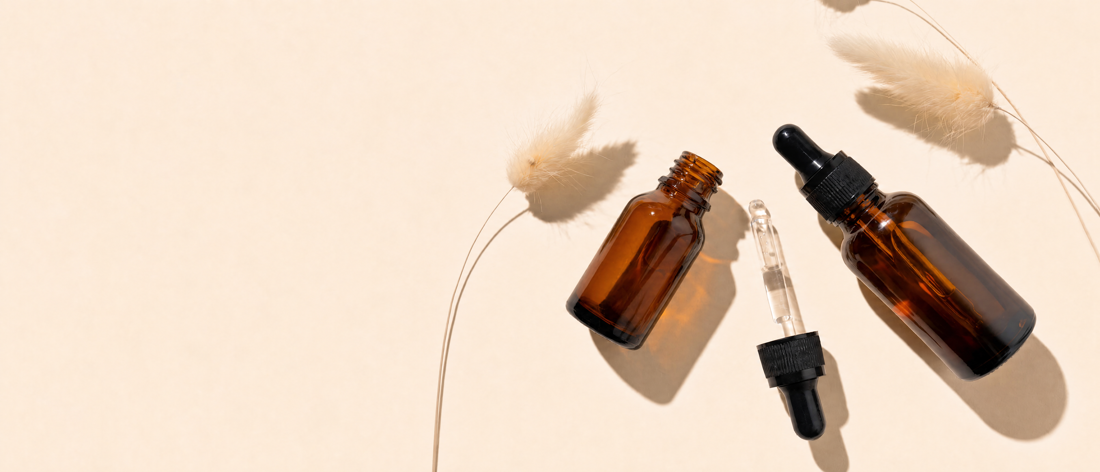 Brown glass bottles with dropper caps on a light background.