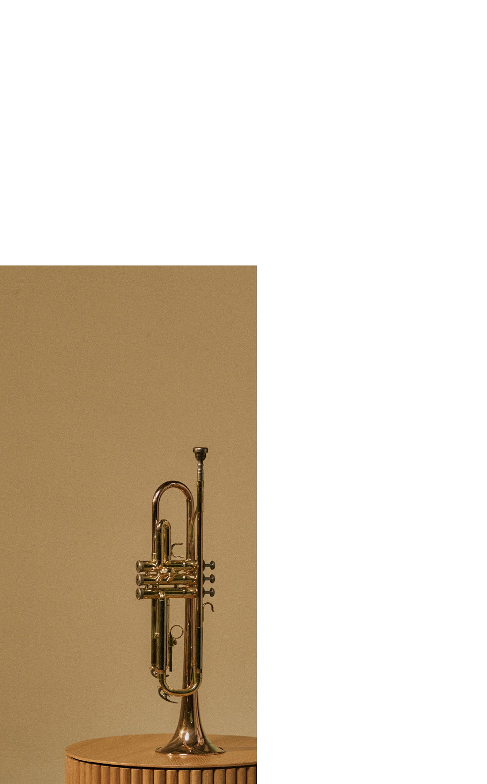 A trumpet resting on a wooden pedestal against a plain background.