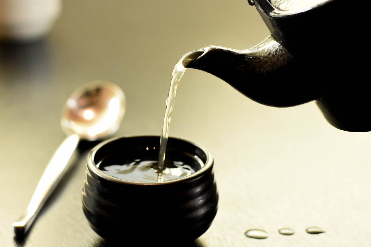A closeup image of hot tea being poured into a small cup