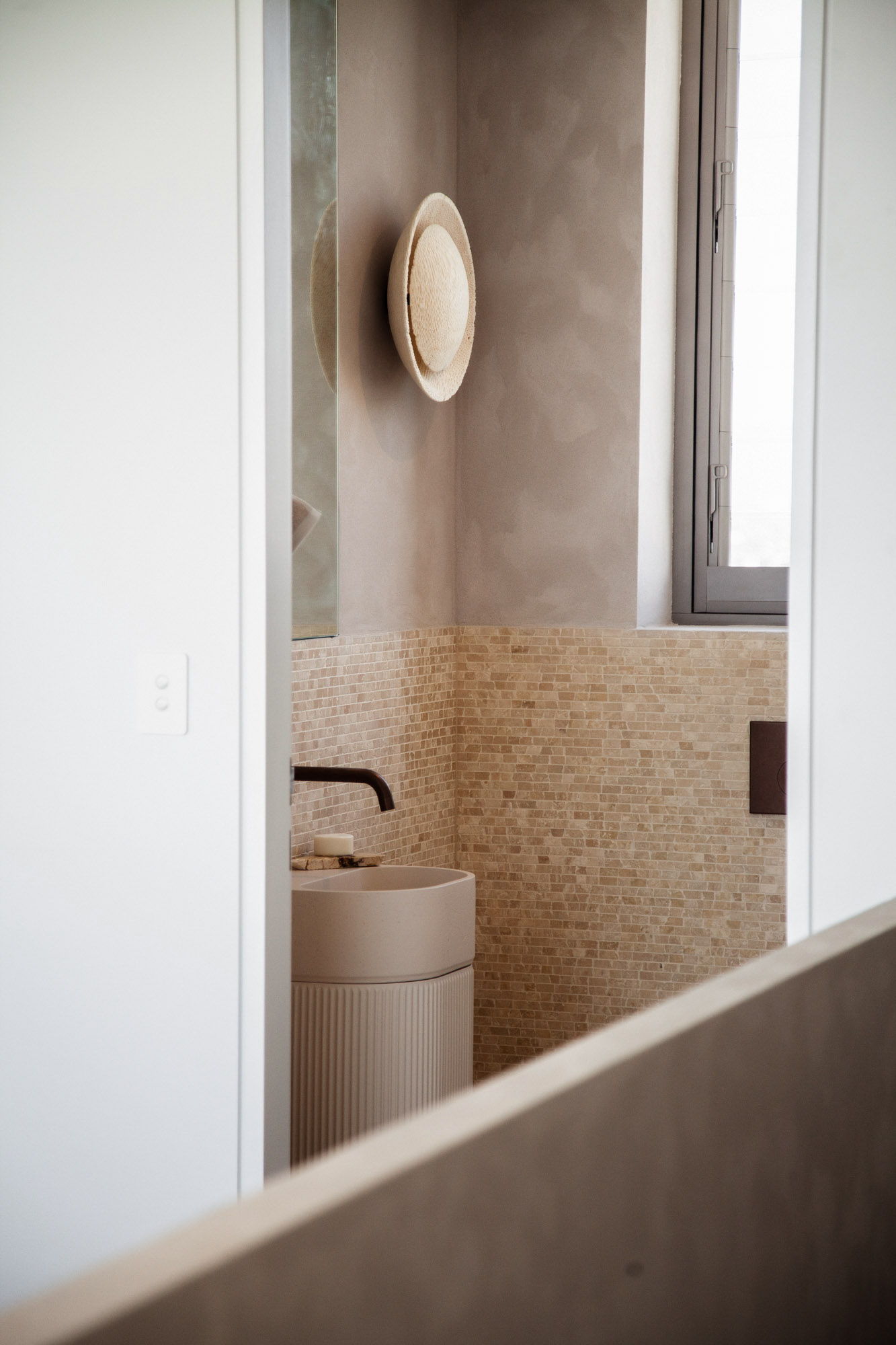 Modern bathroom with textured walls and the Fossil Coral Eclipse Wall Sconce on it.