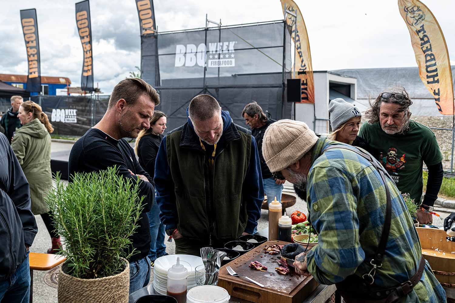 Group of people observing a vendor at an outdoor market.