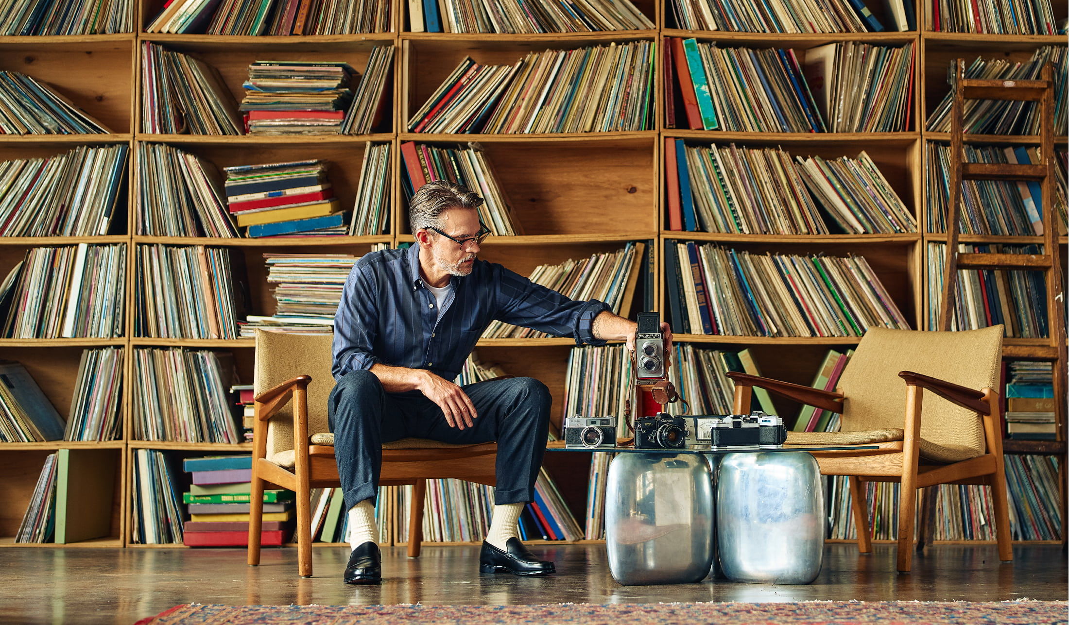 Person sitting in a room full of vinyl records, examining a container.