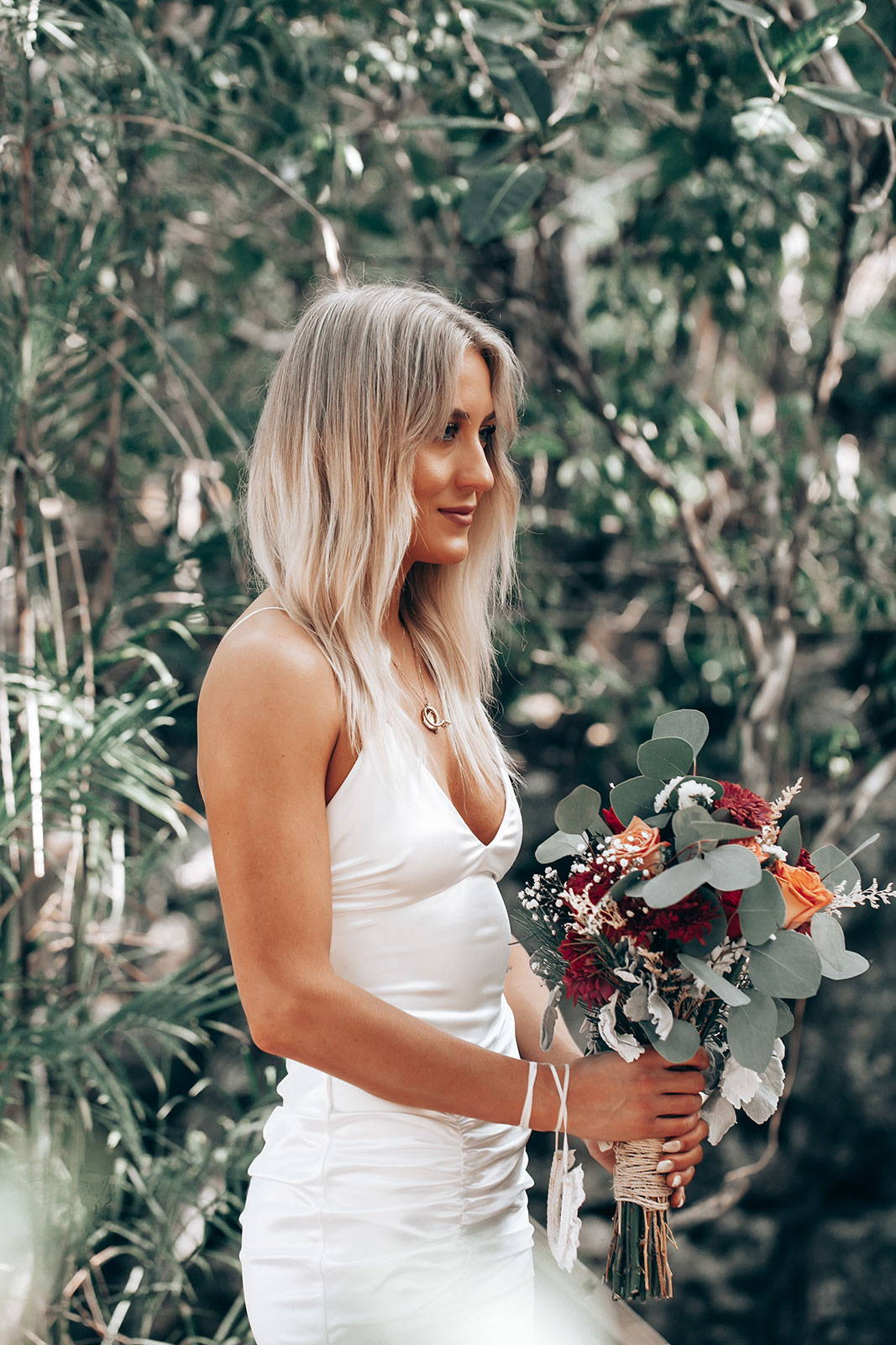 Die Braut hält einen Blumenstrauß und trägt ein Zsa Zsa-Kleid