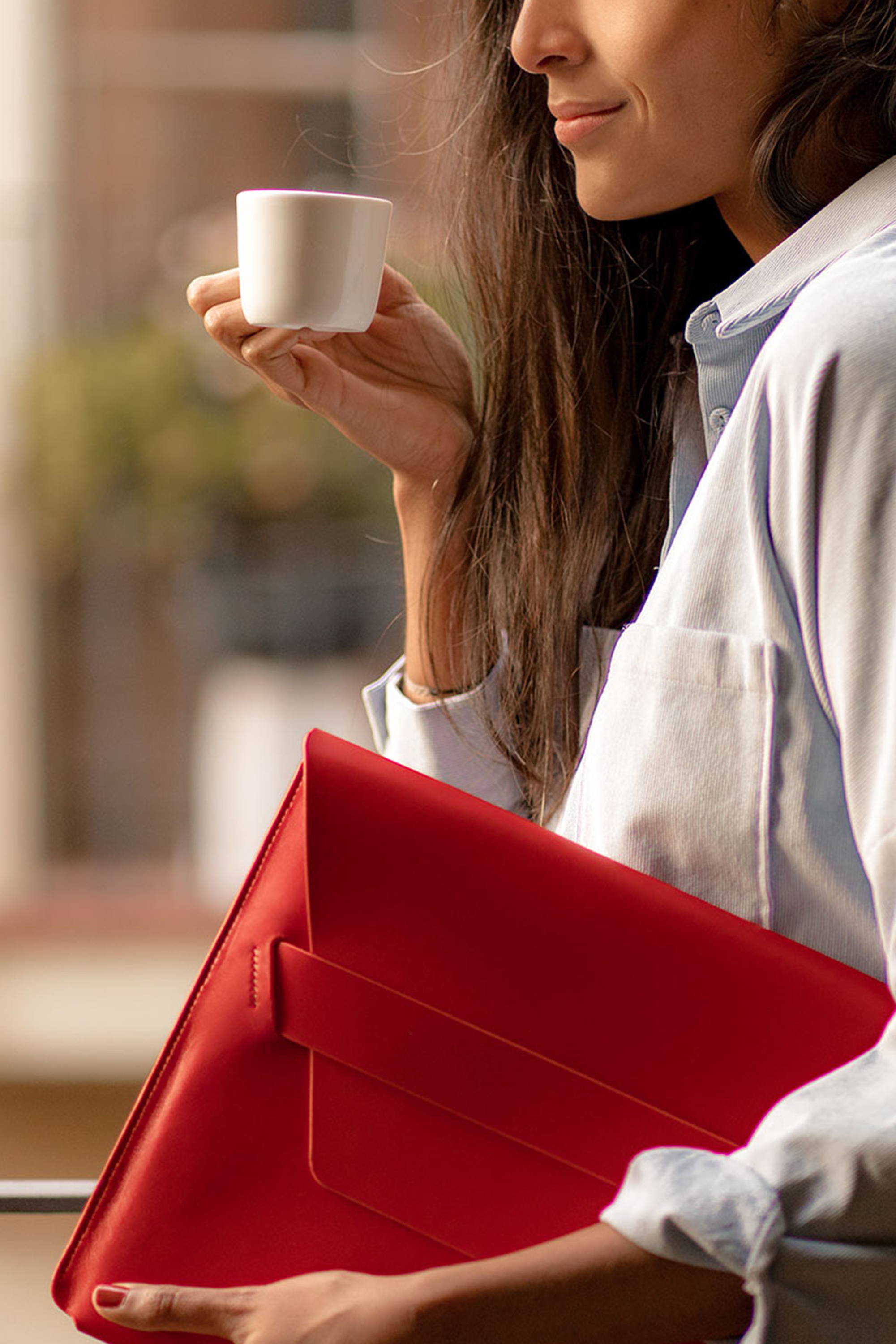 Frau trinkt Kaffee und hält MacBook Hülle Leder Rot Barcelona