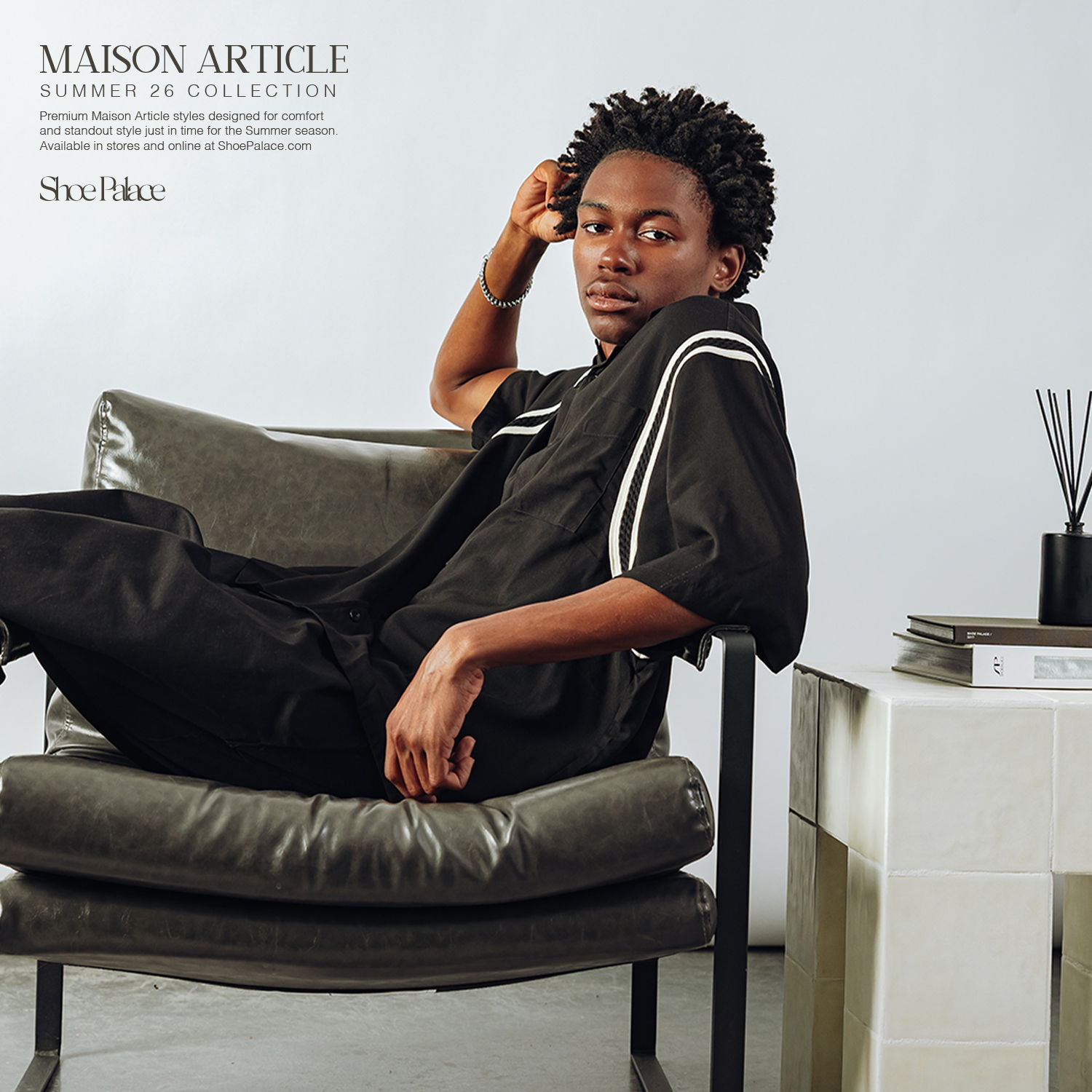 A person sitting casually on a chair, wearing a stylish black outfit.