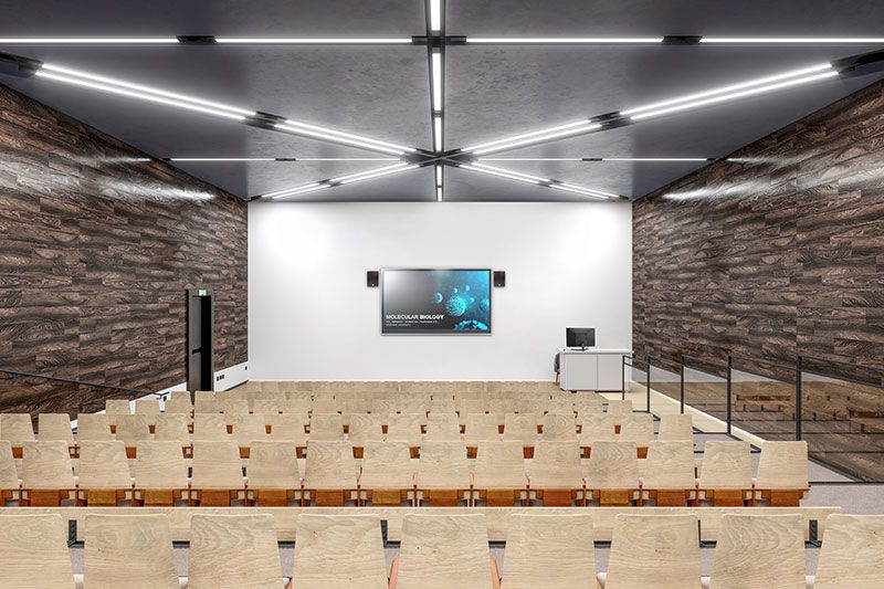crestron auditorium with wooden seating and a large screen at the front.