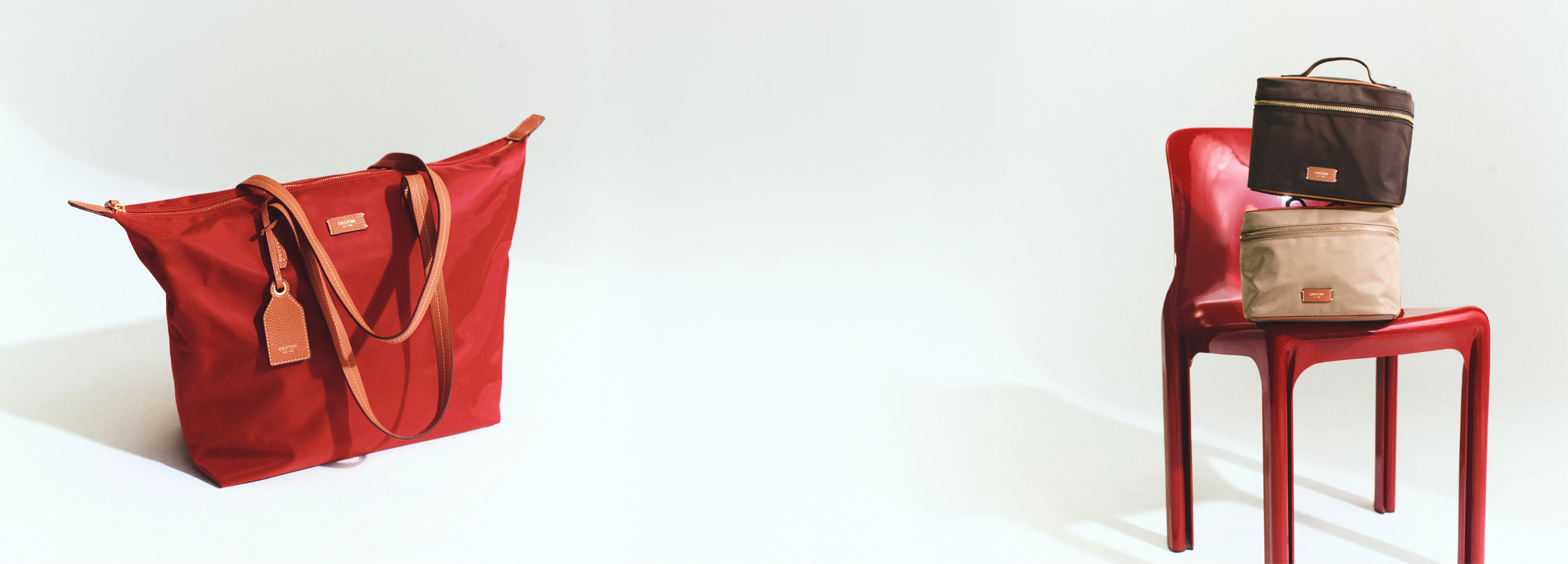 Red tote bag next to stacked bags on a red chair.